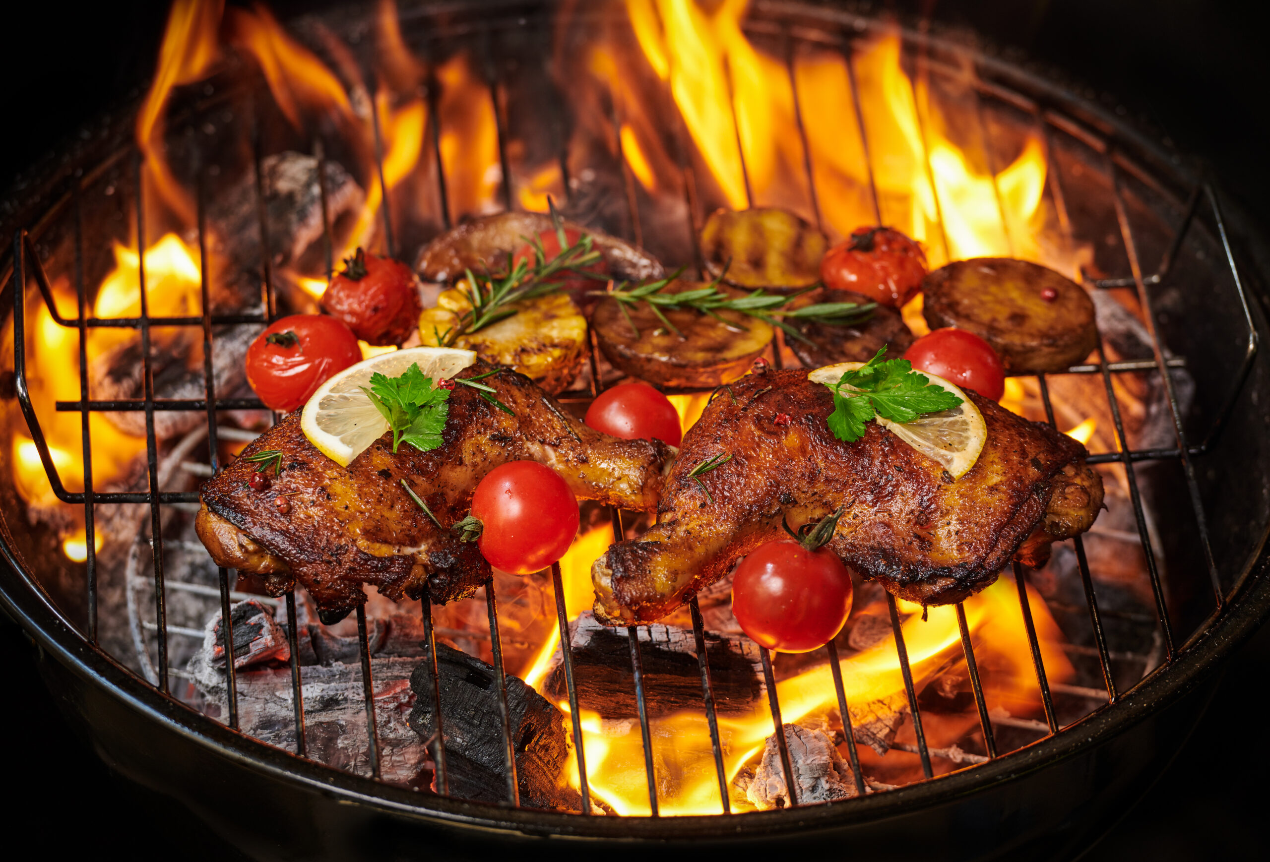 Grilled chicken legs on the flaming grill with grilled vegetable